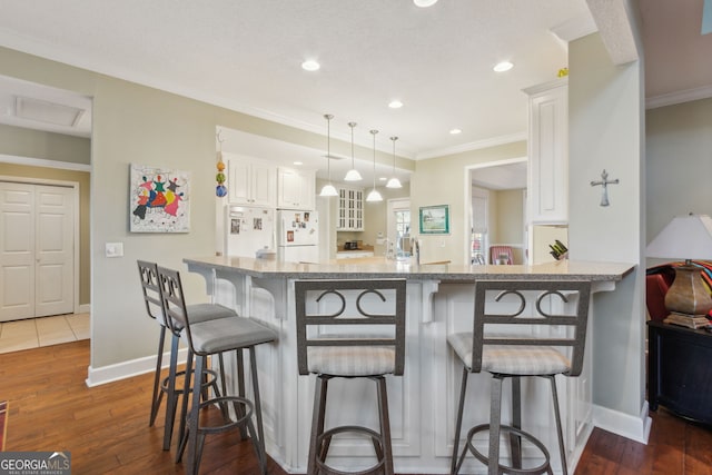 kitchen with dark wood-type flooring, white cabinetry, and a breakfast bar