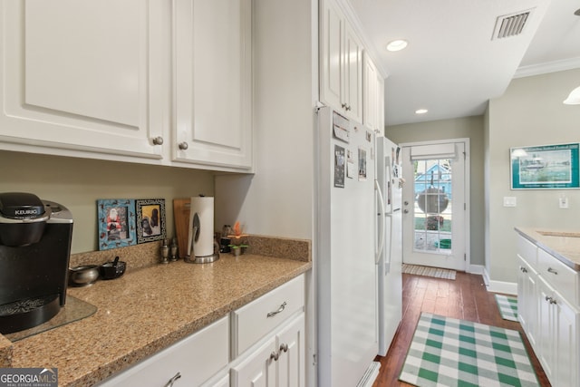kitchen with white cabinets, freestanding refrigerator, dark wood-type flooring, and visible vents
