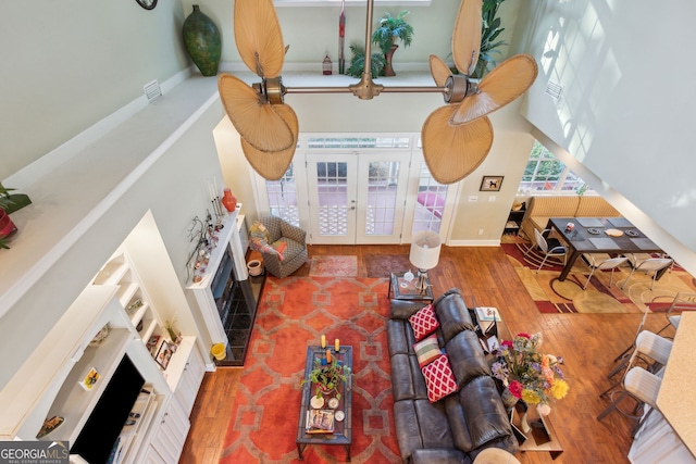 living room featuring french doors, baseboards, a high ceiling, and wood finished floors