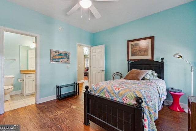 bedroom with baseboards, ensuite bathroom, a ceiling fan, and wood finished floors