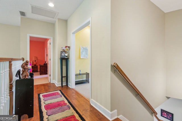 hall featuring visible vents, wood-type flooring, recessed lighting, and an upstairs landing