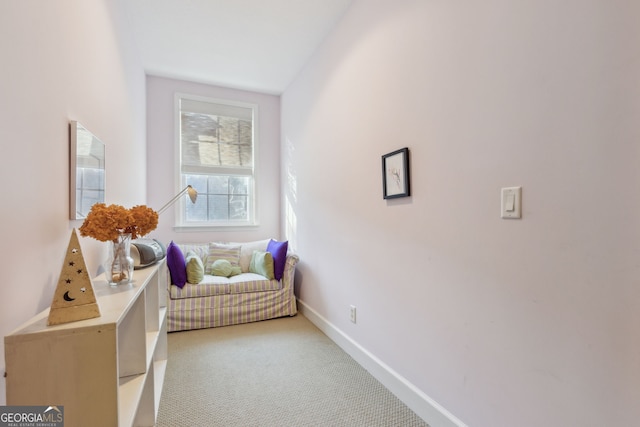 sitting room featuring baseboards and light colored carpet