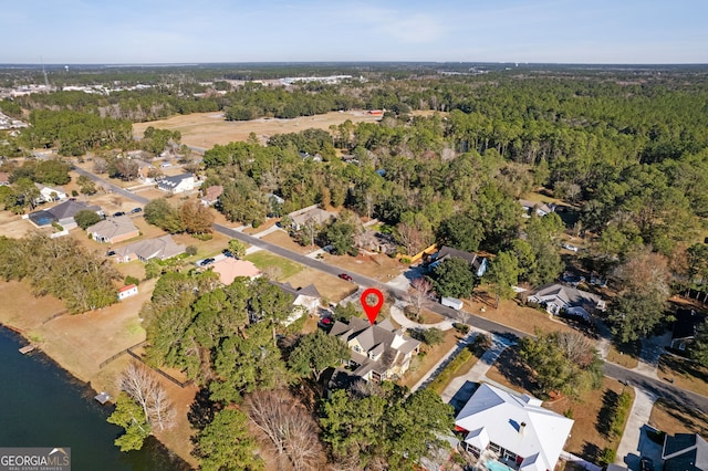 birds eye view of property featuring a forest view and a water view