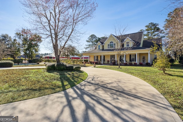 view of front of home with curved driveway, a porch, and a front lawn