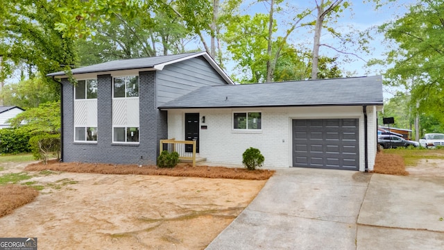 split level home featuring brick siding, a garage, and concrete driveway