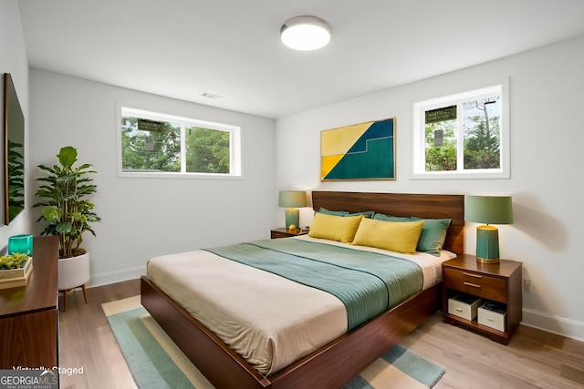 bedroom featuring visible vents, light wood-style flooring, and multiple windows