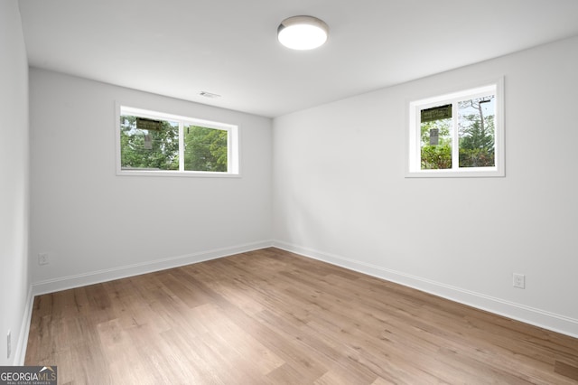 unfurnished room with visible vents, light wood-style flooring, baseboards, and a wealth of natural light