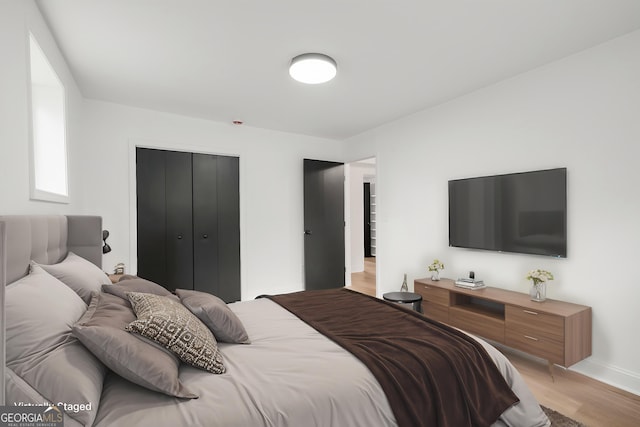 bedroom with a closet, light wood-style flooring, and baseboards