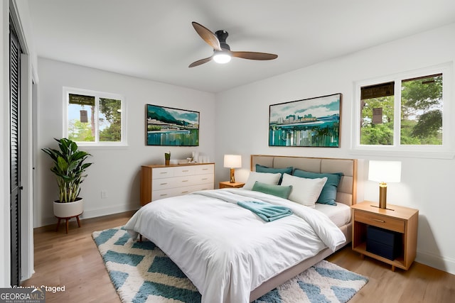 bedroom featuring a closet, baseboards, ceiling fan, and light wood-style floors