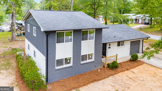view of side of property with a garage, roof with shingles, and brick siding