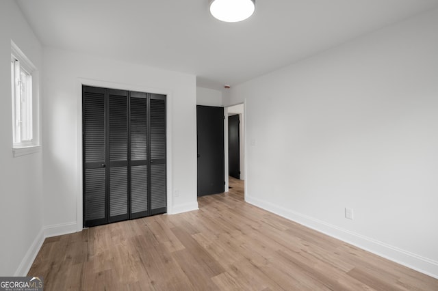 unfurnished bedroom featuring baseboards, a closet, and light wood-type flooring