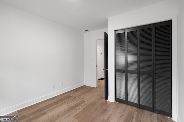unfurnished bedroom featuring baseboards, a closet, and light wood finished floors