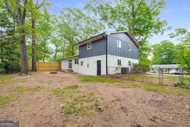 back of property with board and batten siding, fence, a gate, and entry steps