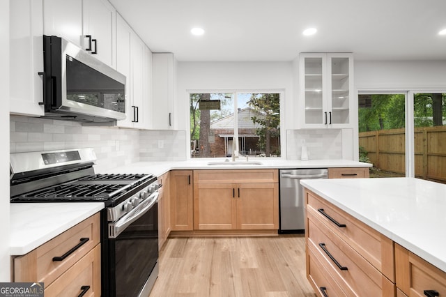 kitchen with a sink, appliances with stainless steel finishes, a wealth of natural light, and light wood-style flooring