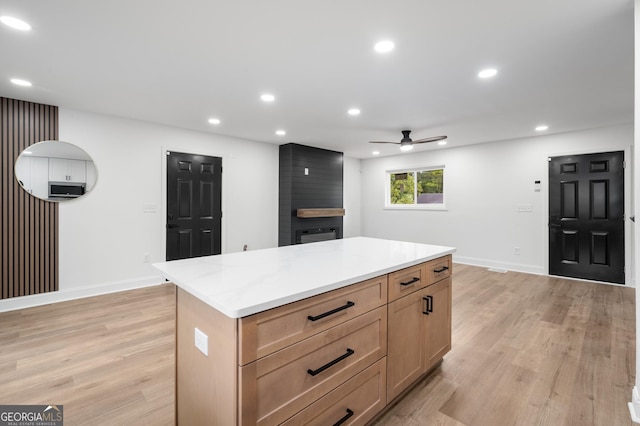 kitchen featuring ceiling fan, a center island, baseboards, and light wood-type flooring