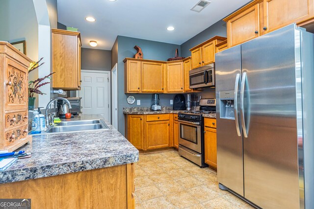 kitchen with appliances with stainless steel finishes, a sink, brown cabinets, and recessed lighting