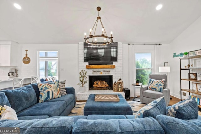 living area featuring a brick fireplace, recessed lighting, a chandelier, and plenty of natural light