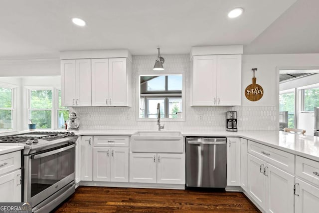 kitchen with appliances with stainless steel finishes, a sink, light countertops, white cabinets, and recessed lighting