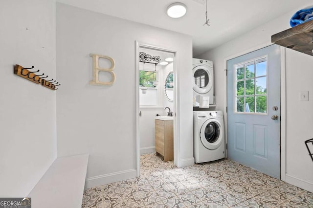 laundry area with laundry area, stacked washer and clothes dryer, baseboards, and a sink