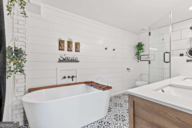 bathroom with wooden walls, a freestanding bath, vanity, toilet, and a stall shower