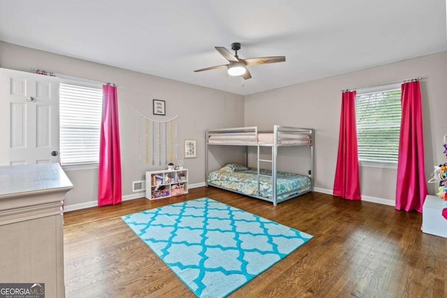 bedroom with baseboards, visible vents, multiple windows, and wood finished floors