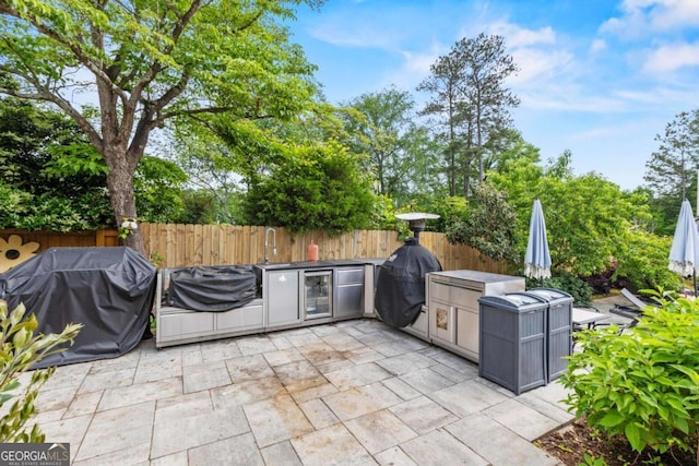 view of patio / terrace featuring area for grilling, fence, and wine cooler