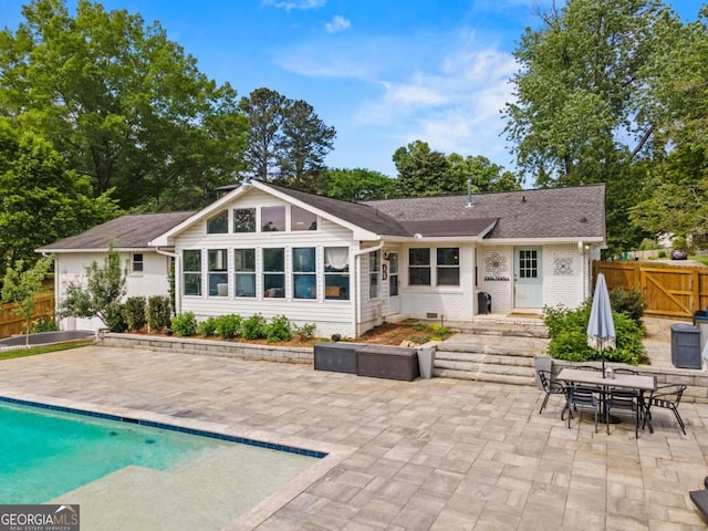 rear view of property featuring a gate, a patio area, brick siding, fence, and a fenced in pool