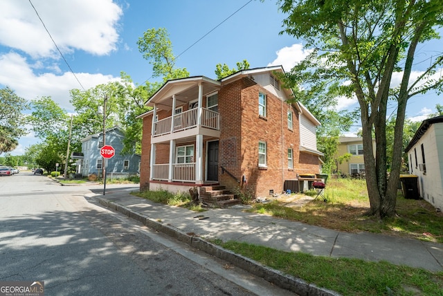 view of side of home featuring brick siding, a balcony, and cooling unit