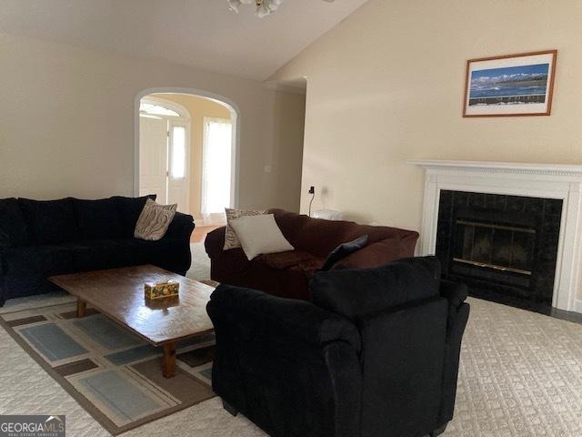 140 Cedar Creek Dr, Dublin, GA 31021 - living room with carpet floors, arched walkways, vaulted ceiling, and a fireplace with flush hearth