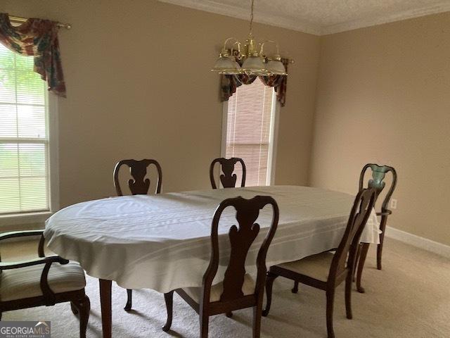 140 Cedar Creek Dr, Dublin, GA 31021 - dining space featuring ornamental molding, light carpet, baseboards, a textured ceiling, and a chandelier