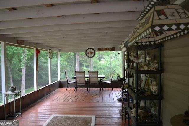 sunroom / solarium featuring beam ceiling, outdoor dining area, and hardwood / wood-style floors