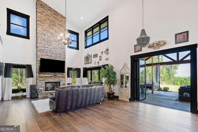 281 Abbott Dr, Canton, GA 30114 - living area featuring a towering ceiling, a chandelier, a stone fireplace, wood finished floors, and healthy amount of natural light