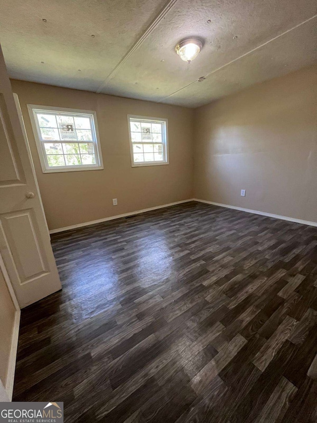 empty room with baseboards and dark wood-style flooring