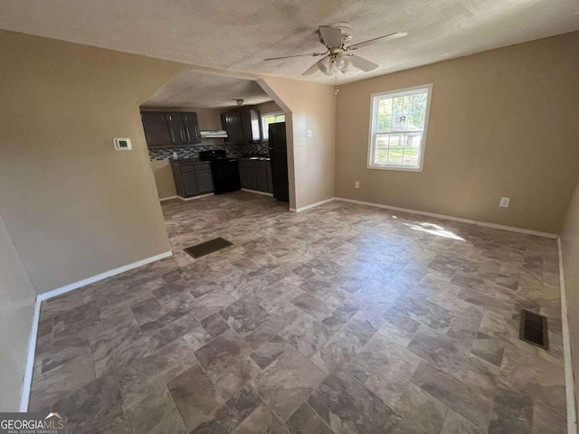 unfurnished living room with ceiling fan, visible vents, and baseboards