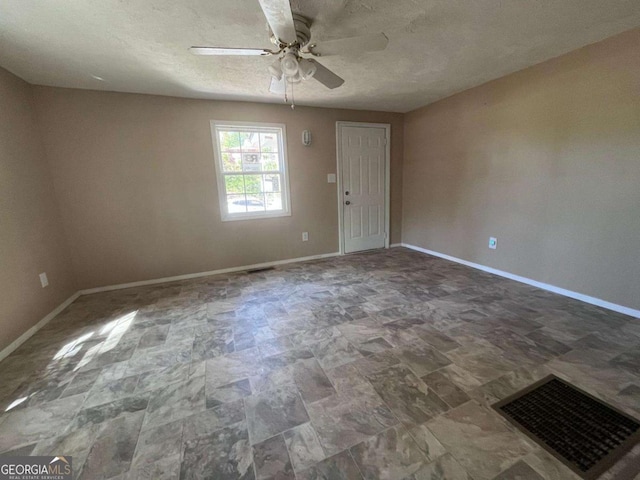 spare room featuring visible vents, a textured ceiling, baseboards, and ceiling fan