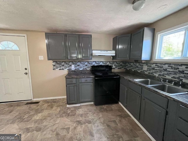 kitchen featuring dark countertops, a sink, backsplash, under cabinet range hood, and black range with electric stovetop