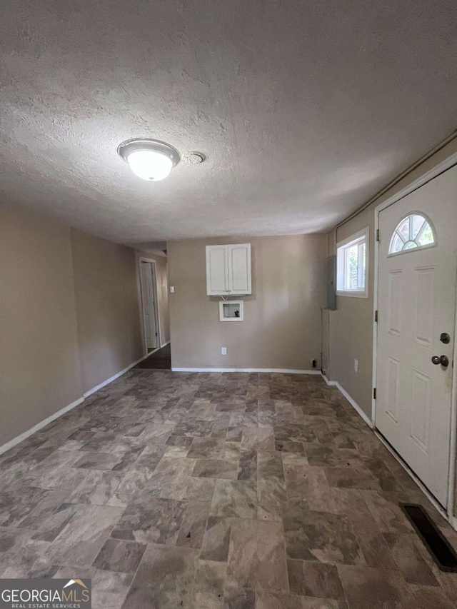 entrance foyer featuring visible vents, stone finish flooring, baseboards, and a textured ceiling