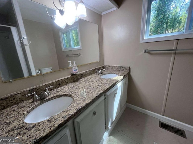 full bath with double vanity, baseboards, visible vents, and a sink