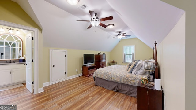 bedroom featuring visible vents, vaulted ceiling, a sink, baseboards, and light wood finished floors