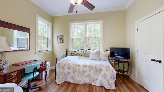 bedroom featuring crown molding, baseboards, wood finished floors, and a closet