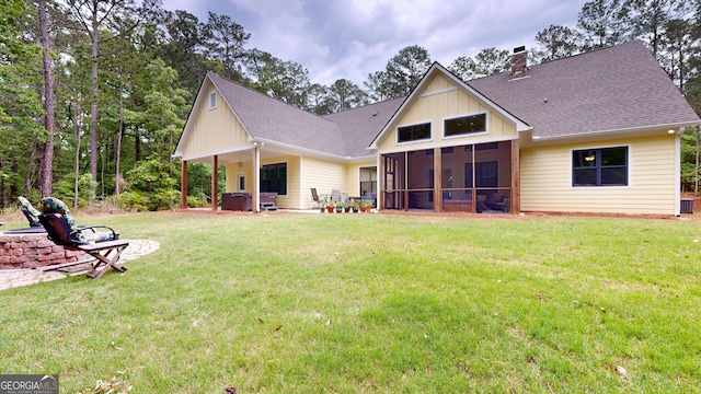 rear view of property with a shingled roof, a hot tub, a sunroom, a chimney, and a yard