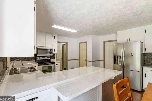 5152 Clearwater Dr, Stone Mountain, GA 30087 - kitchen featuring a peninsula, white cabinetry, a sink, appliances with stainless steel finishes, and backsplash