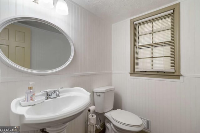 5152 Clearwater Dr, Stone Mountain, GA 30087 - half bathroom featuring visible vents, wainscoting, toilet, a textured ceiling, and a sink
