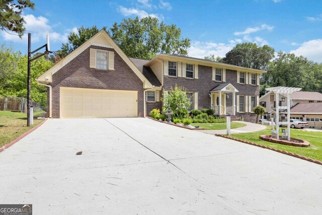 5152 Clearwater Dr, Stone Mountain, GA 30087 - colonial-style house with brick siding, a garage, a front yard, and concrete driveway