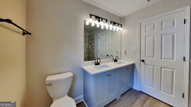 931 Justin Dr, Winder, GA 30680 - bathroom featuring a sink, toilet, a textured ceiling, and wood finished floors
