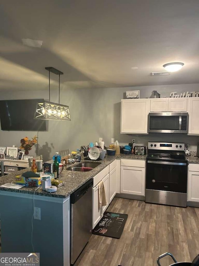 713 Dove Tree Ln, Social Circle, GA 30025 - kitchen with white cabinets, appliances with stainless steel finishes, a sink, wood finished floors, and visible vents