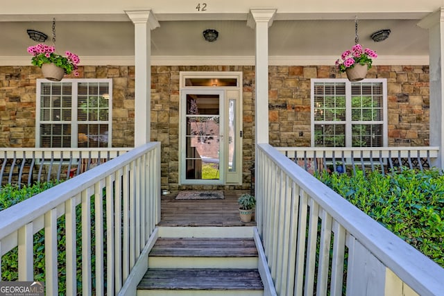 entrance to property with covered porch and stone siding