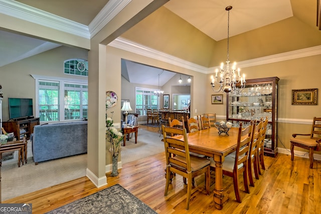 dining room with an inviting chandelier, ornamental molding, lofted ceiling, baseboards, and light wood-type flooring