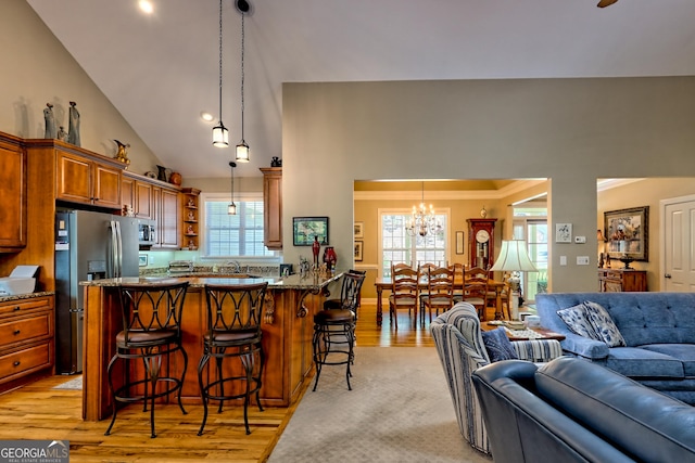 kitchen featuring a breakfast bar area, open shelves, stainless steel fridge with ice dispenser, open floor plan, and an inviting chandelier