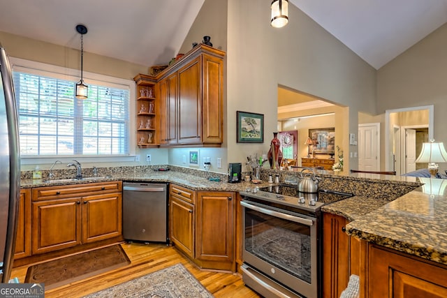 kitchen with a sink, appliances with stainless steel finishes, brown cabinetry, and high vaulted ceiling